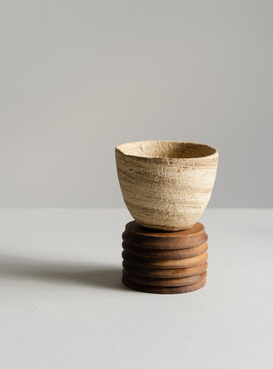 Ceramic cup on a wooden stand against a plain background