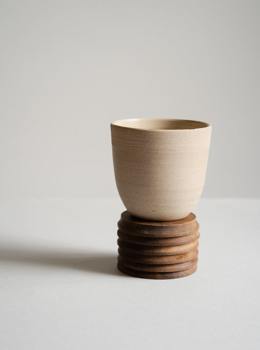 Ceramic cup on a wooden stand against a plain background