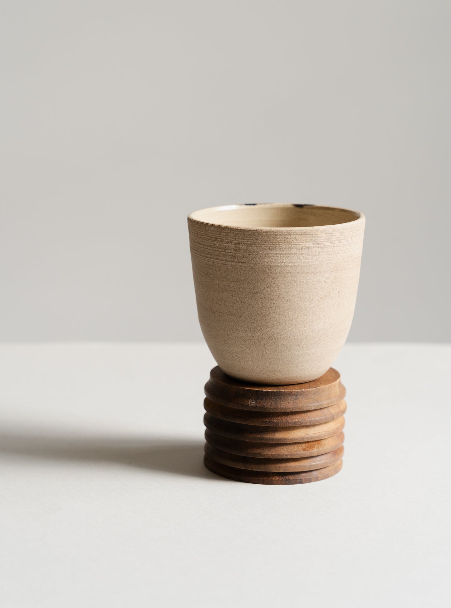 Ceramic cup on a wooden stand against a plain background