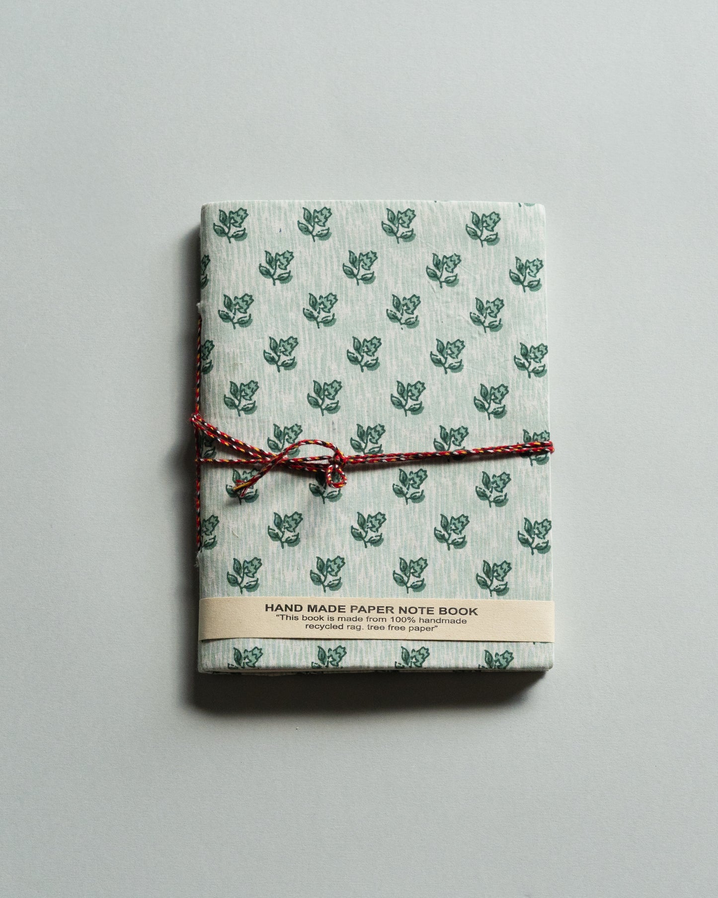 Handmade paper notebook with green leaf pattern on a gray background