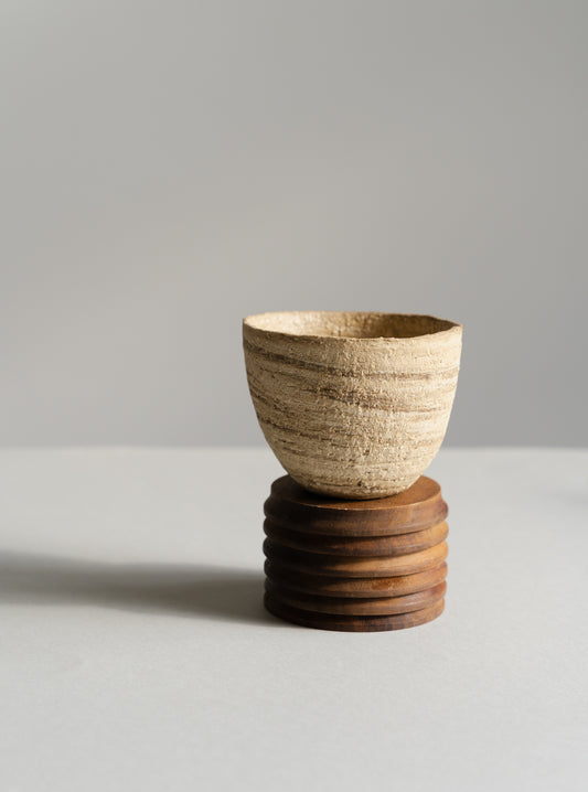 Ceramic cup on a wooden stand against a gray background