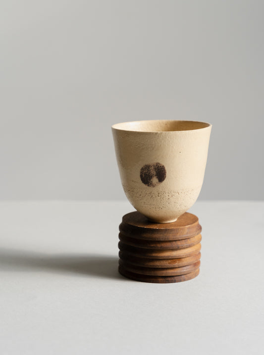 Ceramic cup on a wooden base against a light grey background